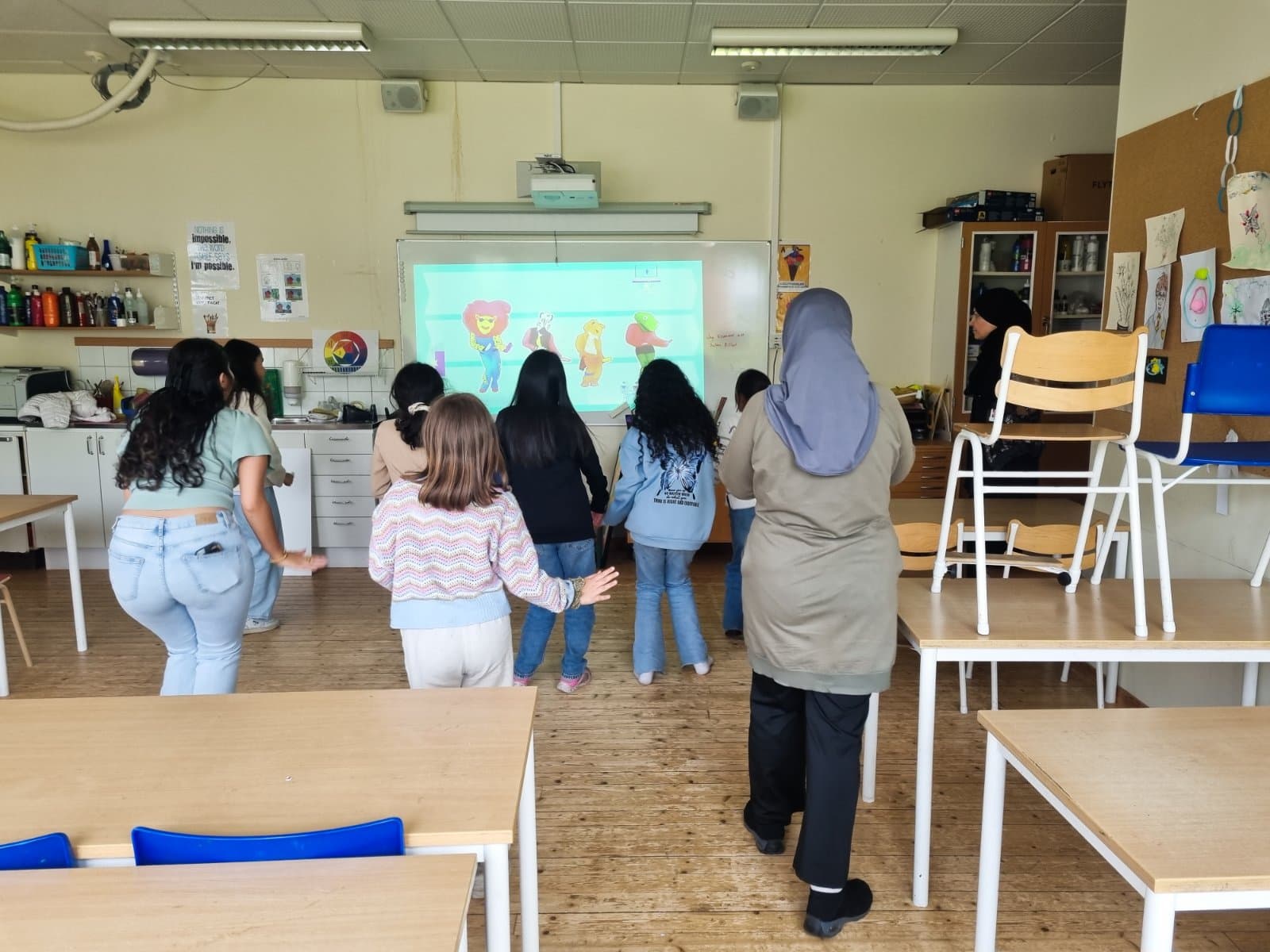 Barn samlade framför en skärm i ett klassrum under en teknikträff