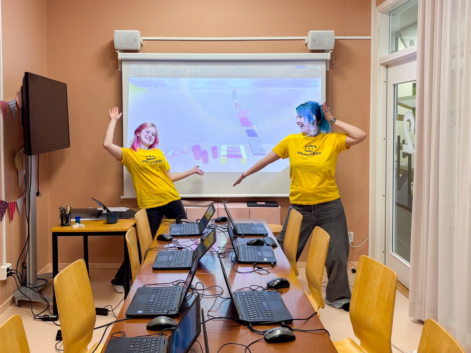 Två unga ledare i gula tröjor leder en övning framför projektorduken